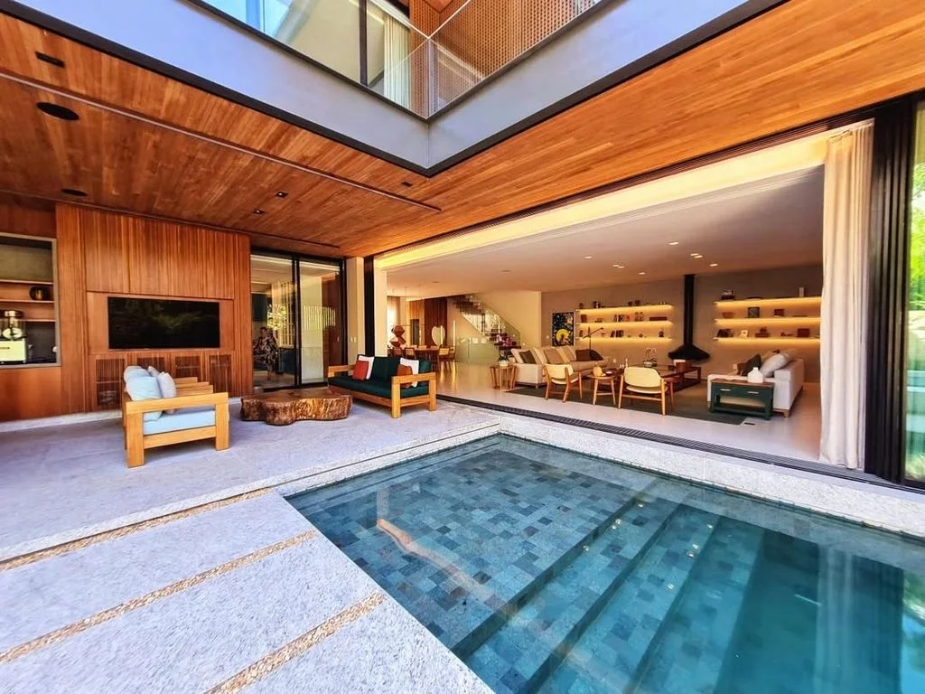 Living integrado à piscina, com lareira e estantes iluminadas