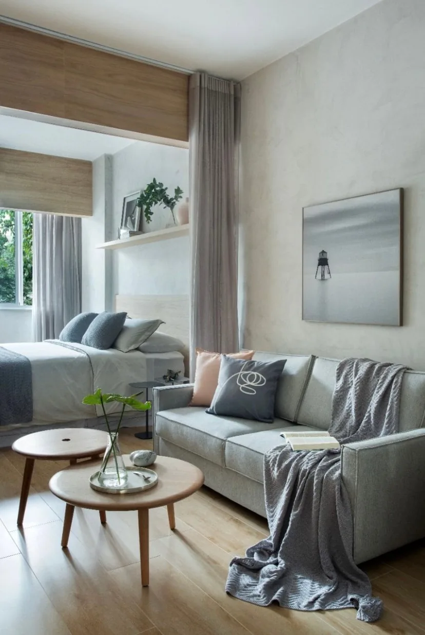 Sala com sofá e mesas de centro, cama ao fundo