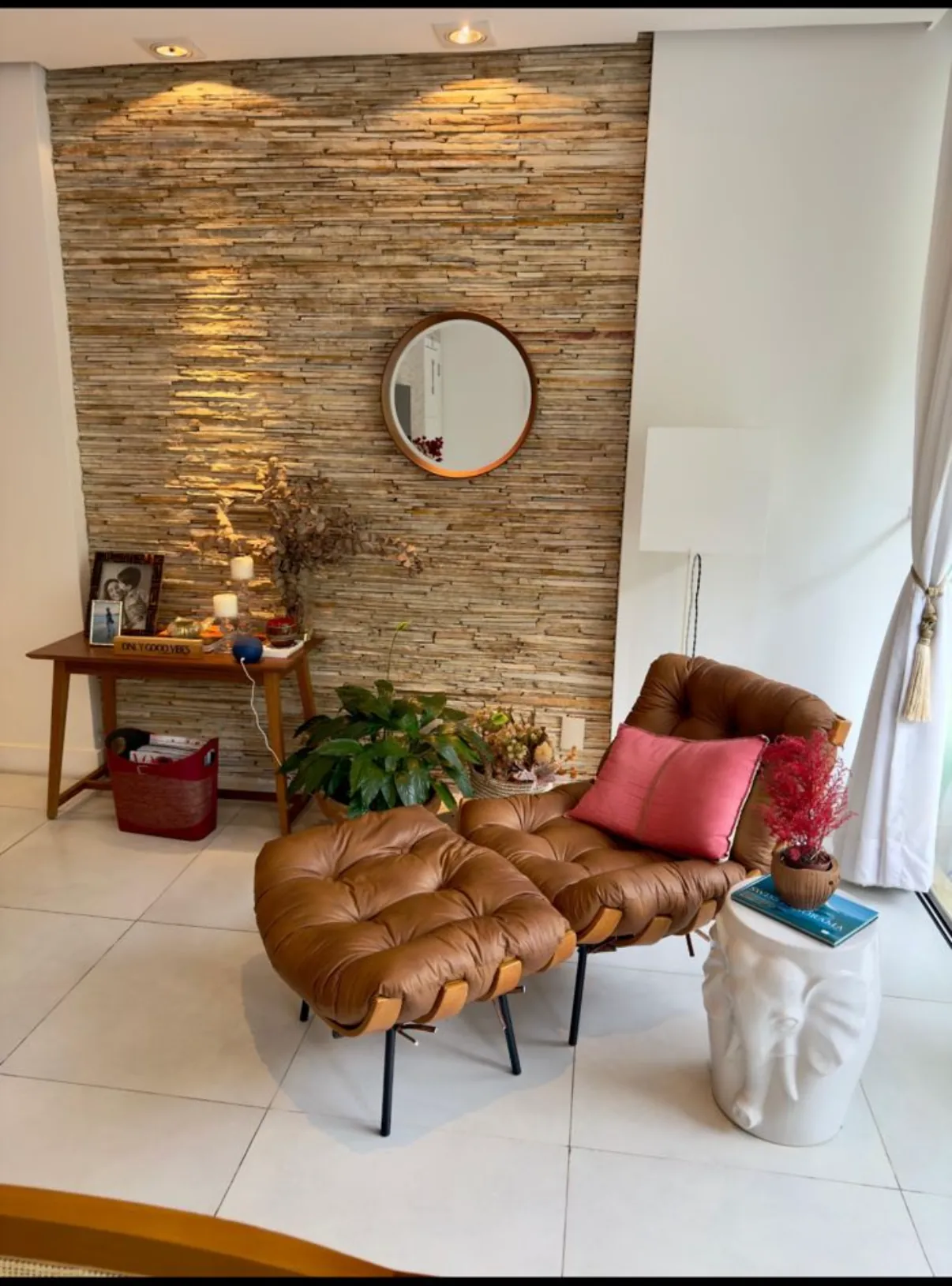 Cantinho da sala com poltrona de couro e parede de pedra