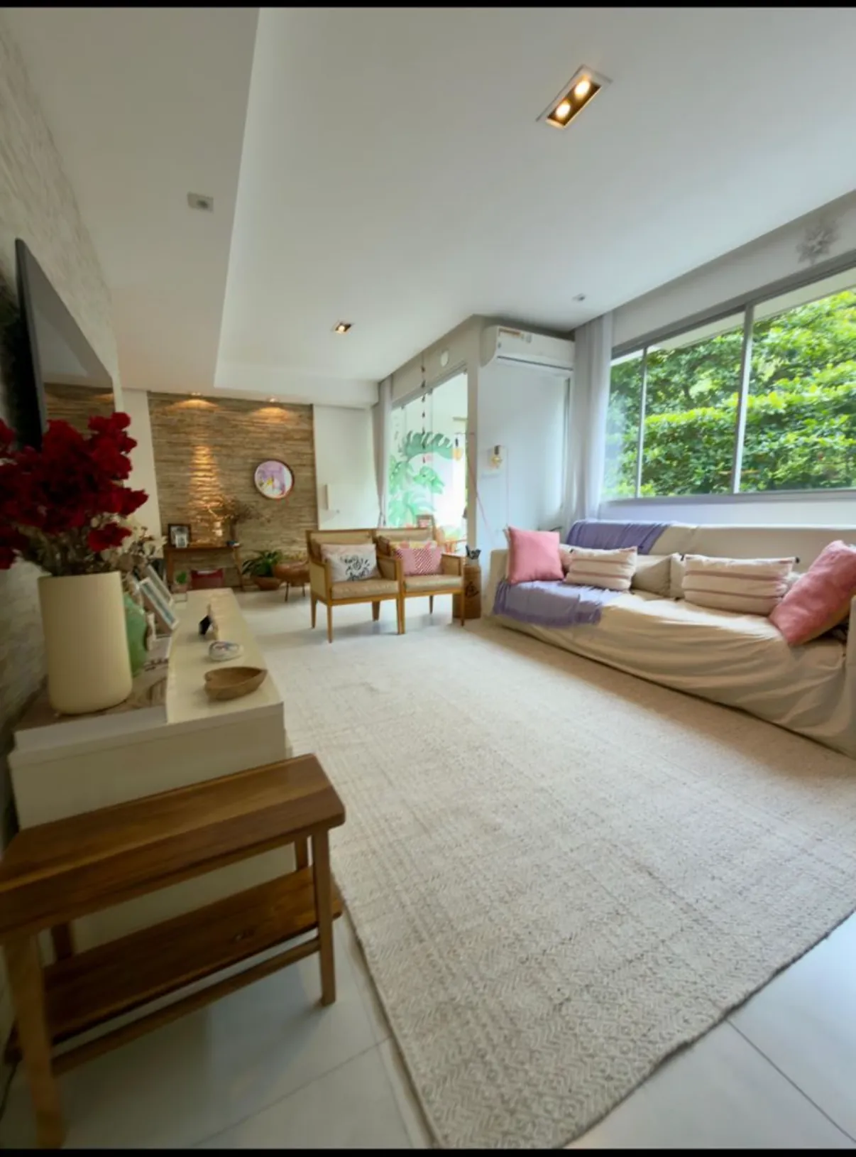 Sala de estar com sofá e janelões com vista para o verde