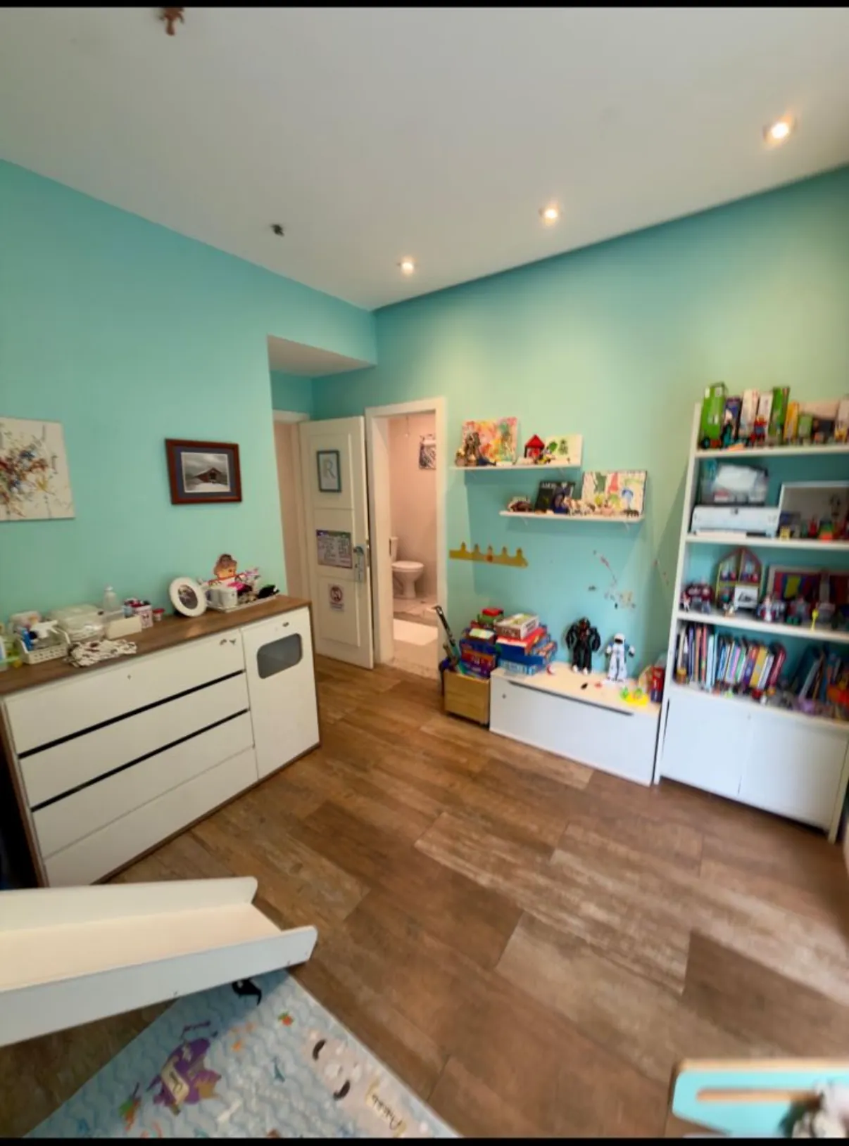Quarto decorado com estante e cômoda brancas