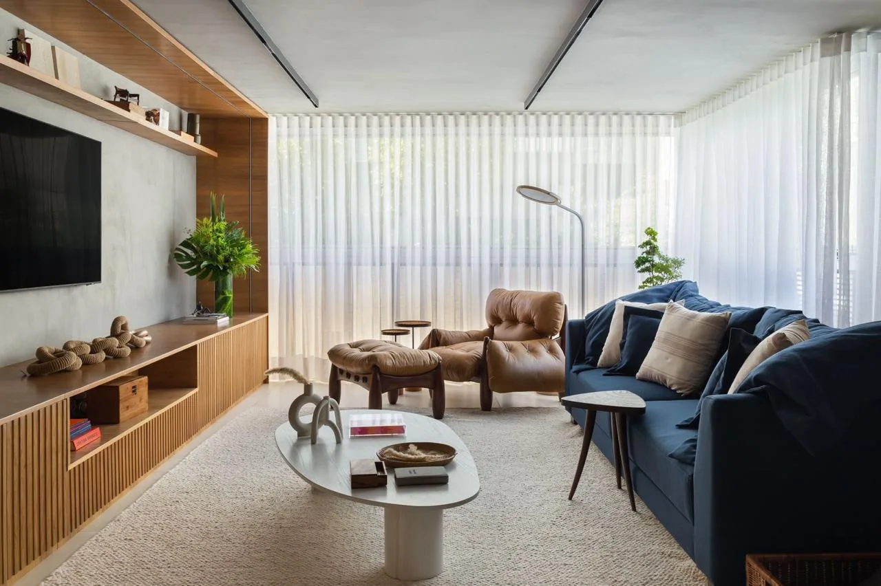 Living integrado com poltronas de couro e cortinas voile
