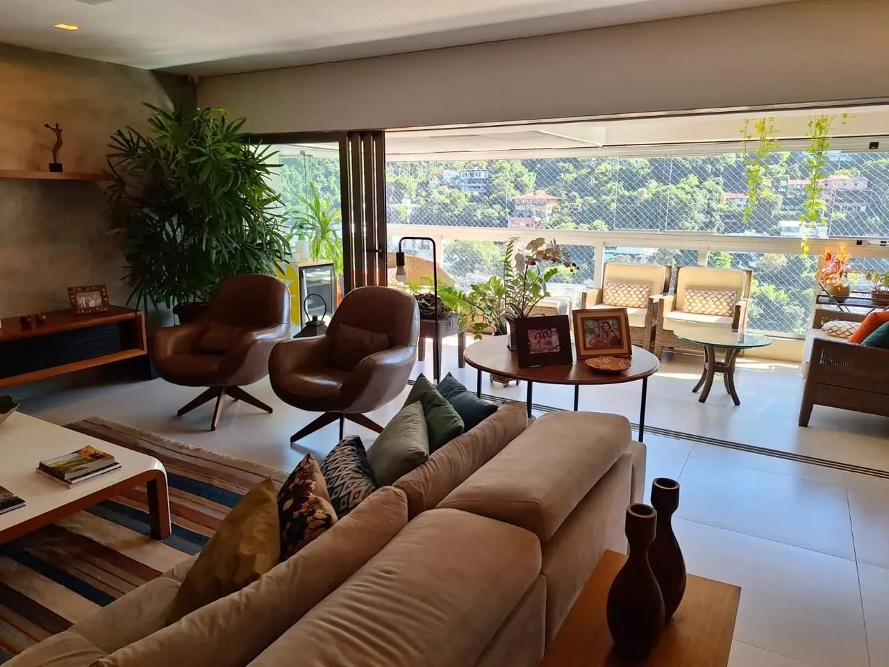 Sala de estar integrada à varanda, com vista para o verde